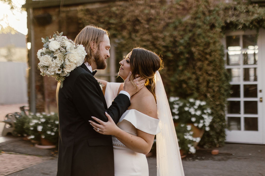 A bride and groom embrace facing each other while basking in golden hour glow outside of Blanc Denver